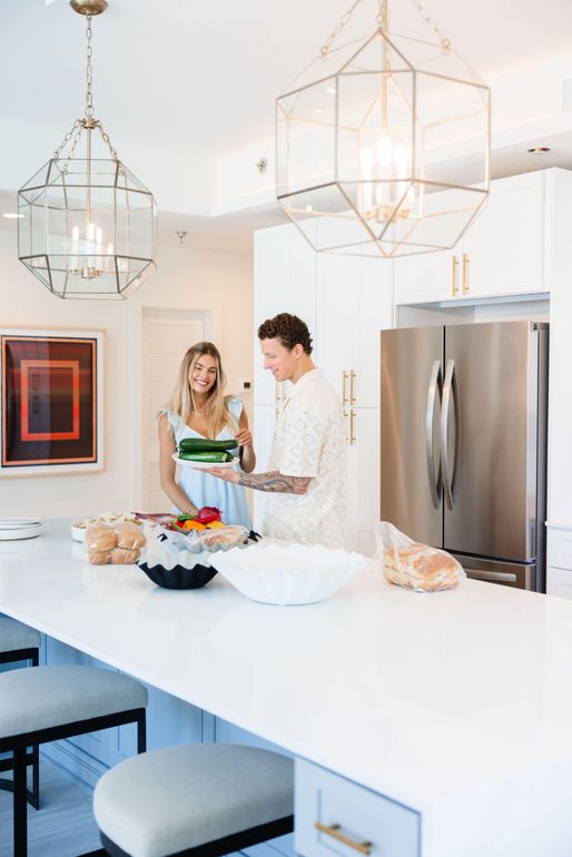 A man and a woman are standing in a kitchen preparing food.