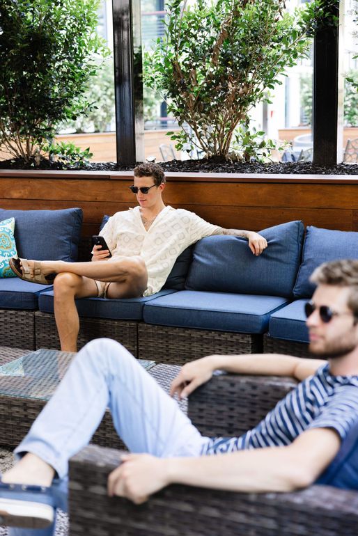 Two men are sitting on a couch looking at their phones.