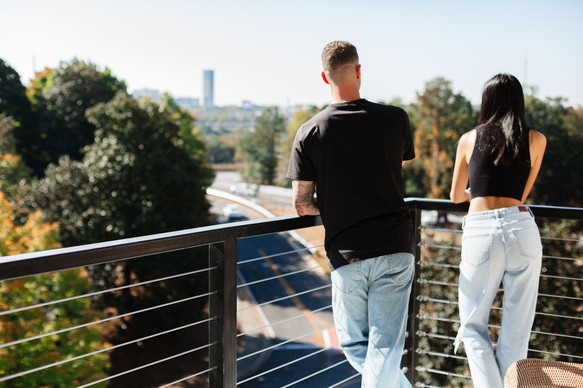 A man and a woman are standing on a balcony overlooking a city.