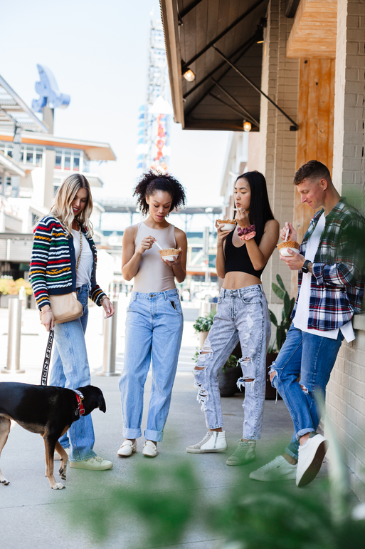 A group of people are standing on a sidewalk with a dog.