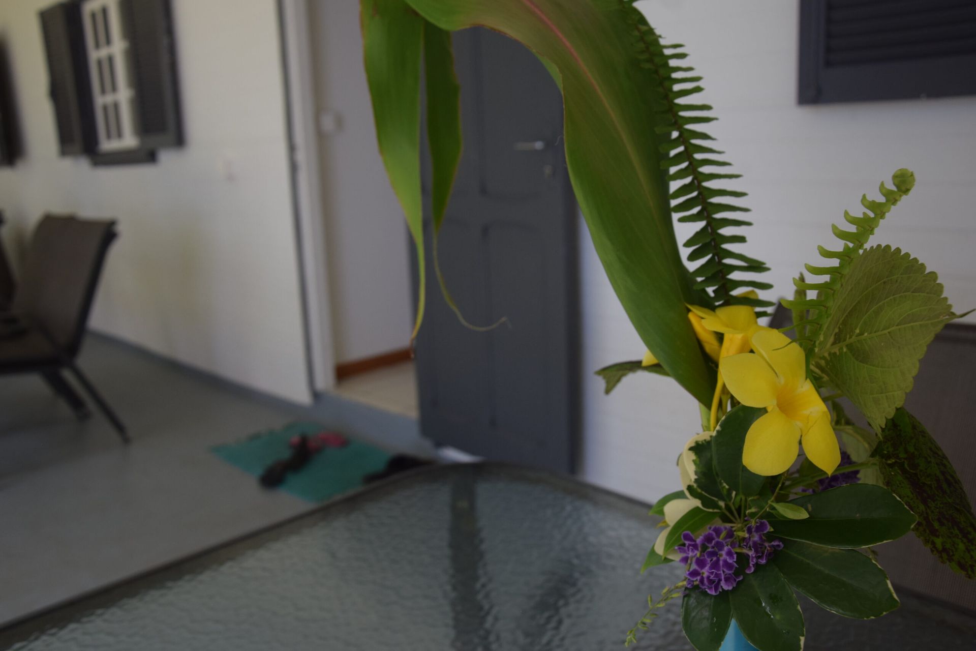 Un vase de fleurs est posé sur une table en verre dans un salon.
