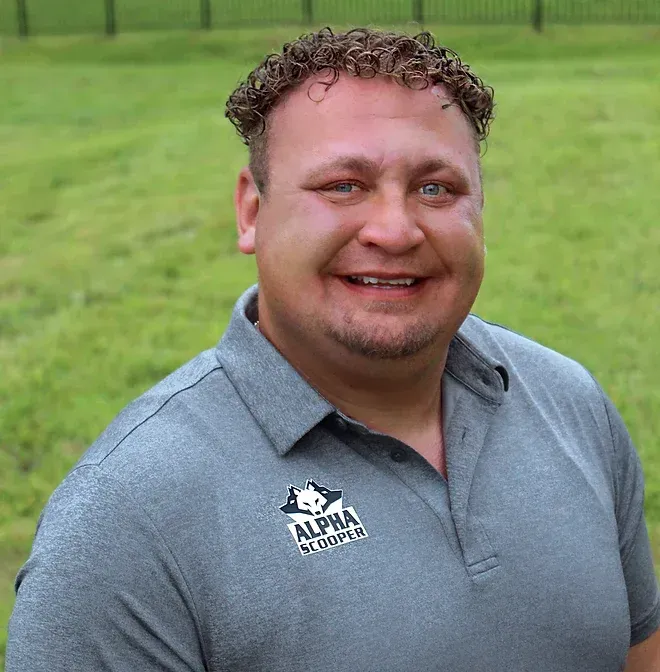 A man wearing a grey shirt with the word alpha on it