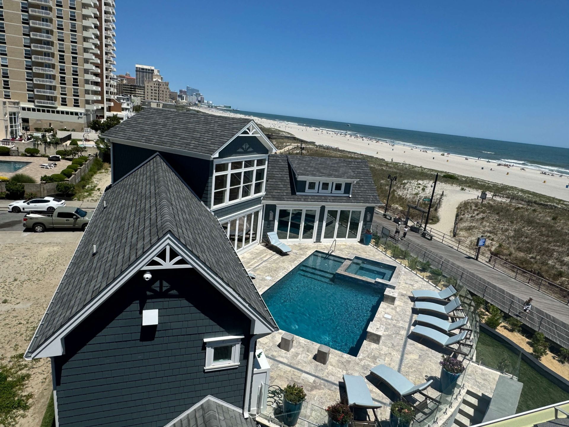 Aerial view of a beach house with a pool beside a sandy shoreline and ocean.
