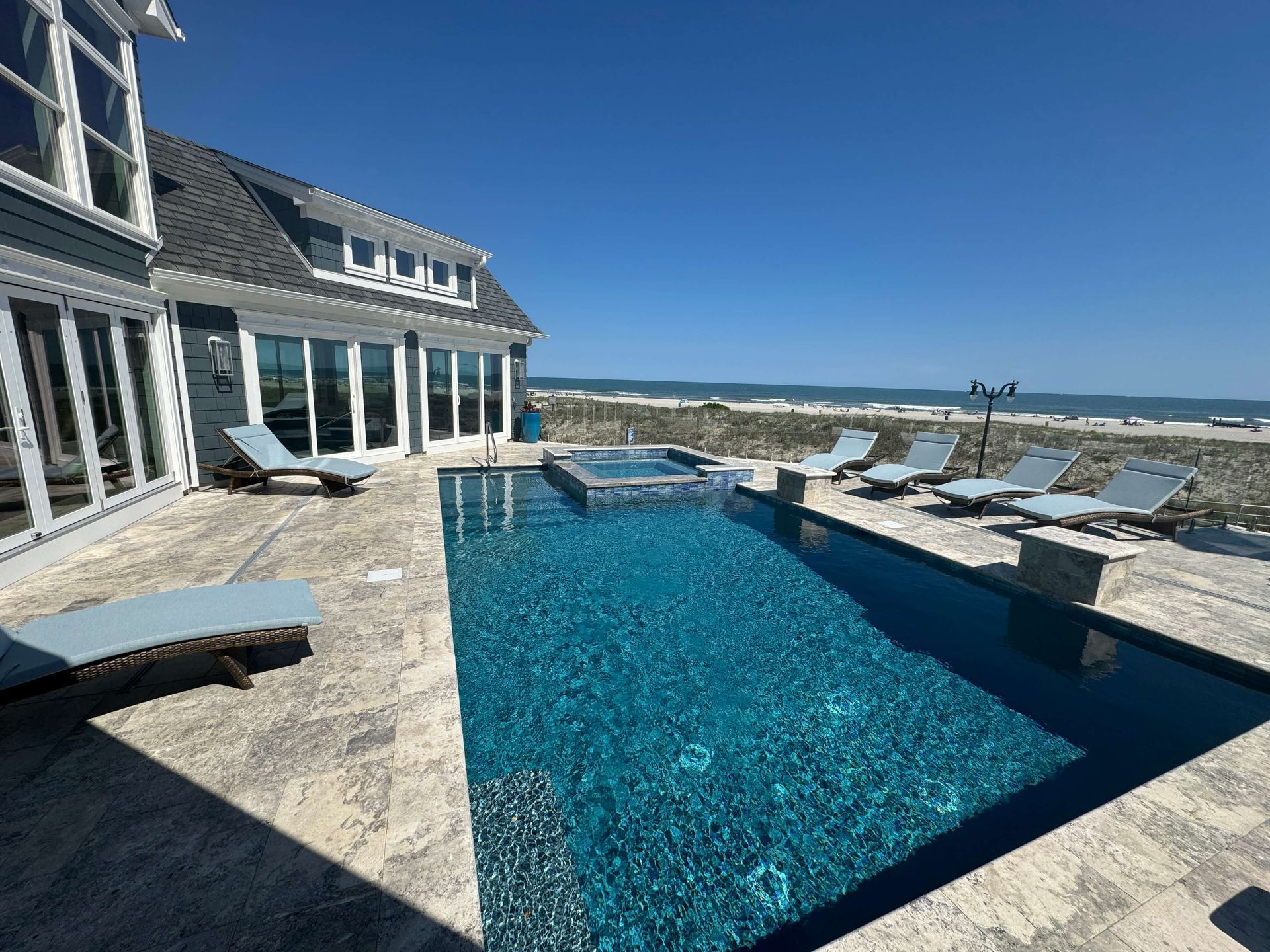 Luxury waterfront patio with a blue infinity pool overlooking the ocean