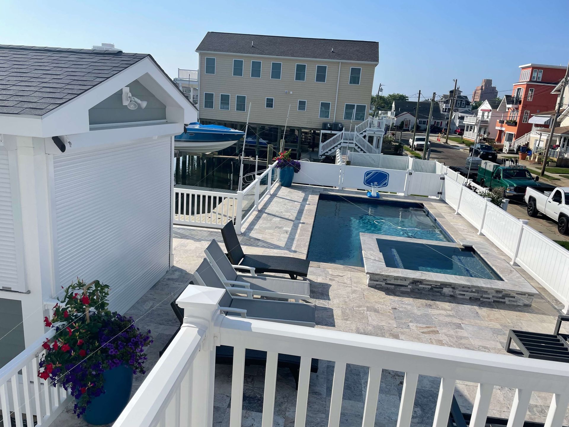 Coastal pool deck with blue swimming pool, lounge chairs, and white railings beside beach houses