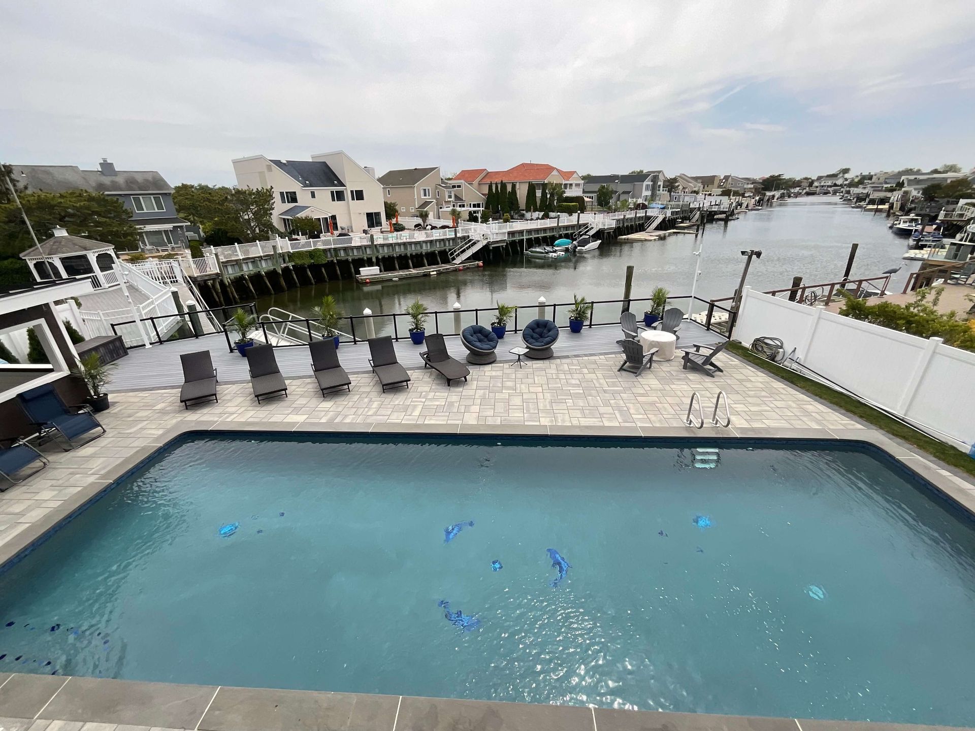 Riverside patio with a swimming pool and lounge chairs overlooking a canal and houses