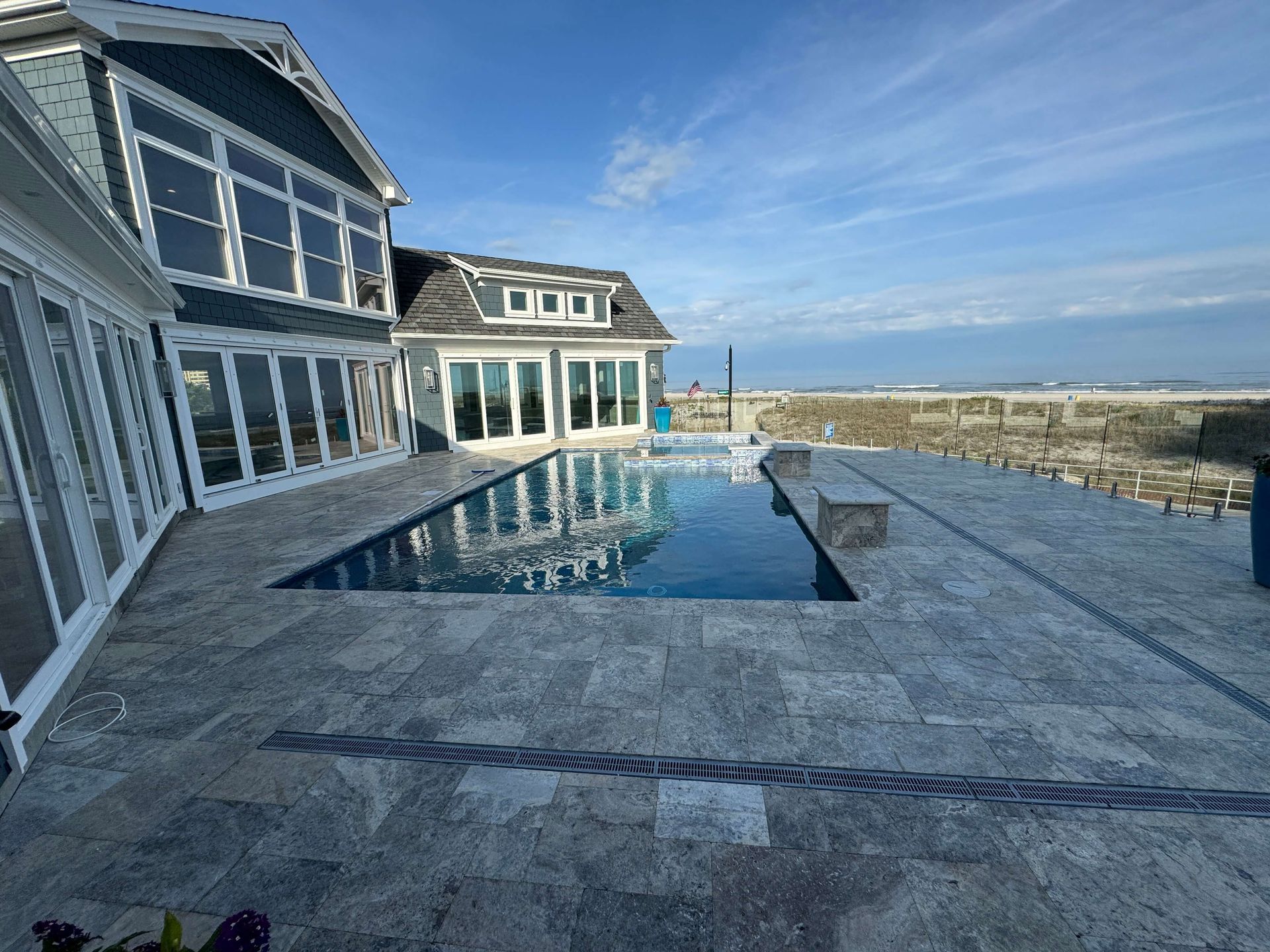 Oceanfront house with a pool and stone patio overlooking the water