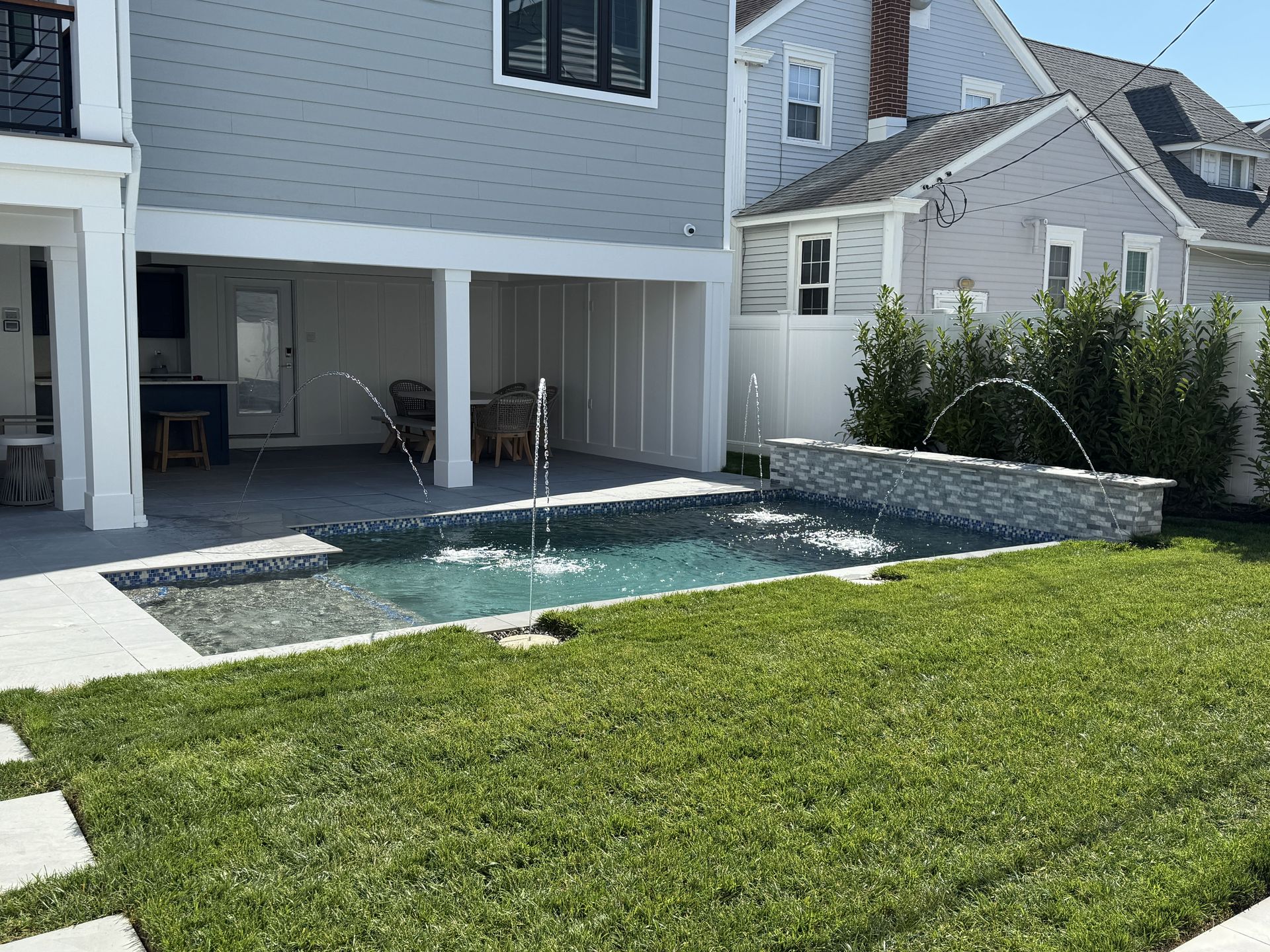 Backyard with a small rectangular pool beside a house and green lawn