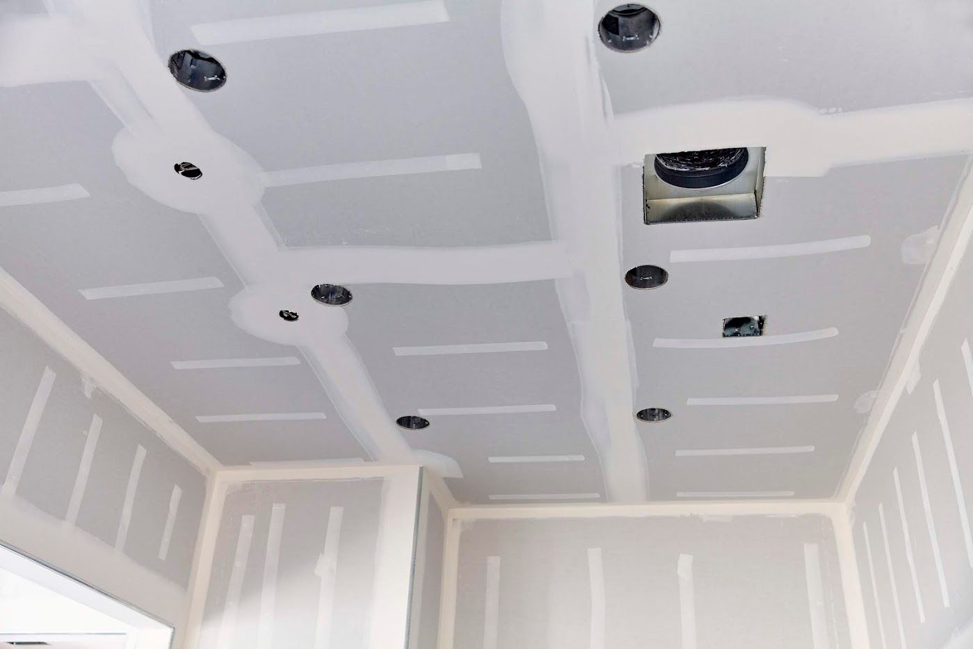 Unfinished room ceiling with drywall seams, recessed light cutouts, and a vent opening