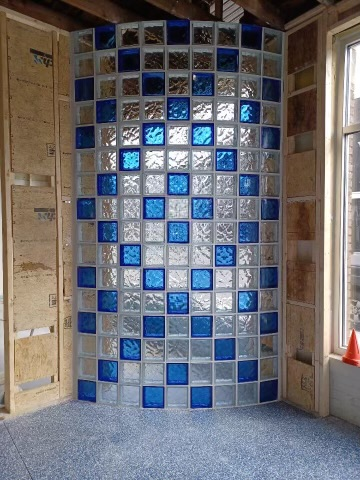 Blue mosaic-tiled shower alcove with glass-block wall and a window beside it