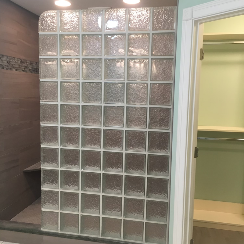 Bathroom with glass-block shower wall, tiled walls, and an open built-in shelf unit