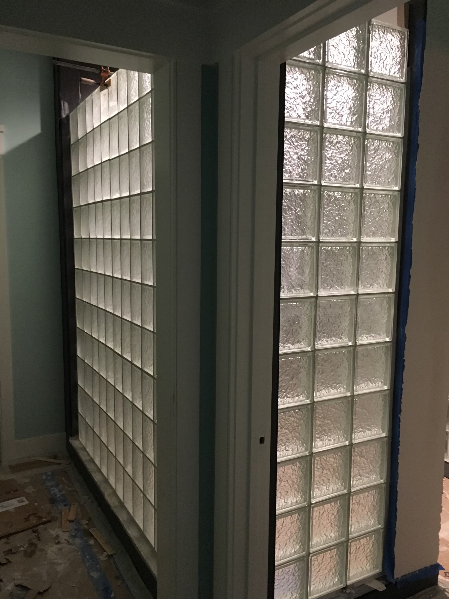 Narrow hallway with glass block wall panels and a partially visible blue-painted doorframe