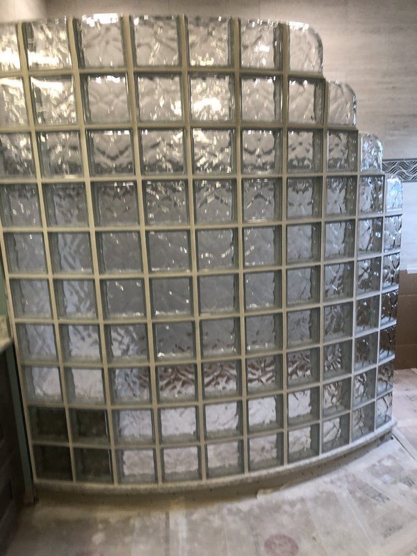 Curved glass block wall with frosted and clear panels in a tiled interior space
