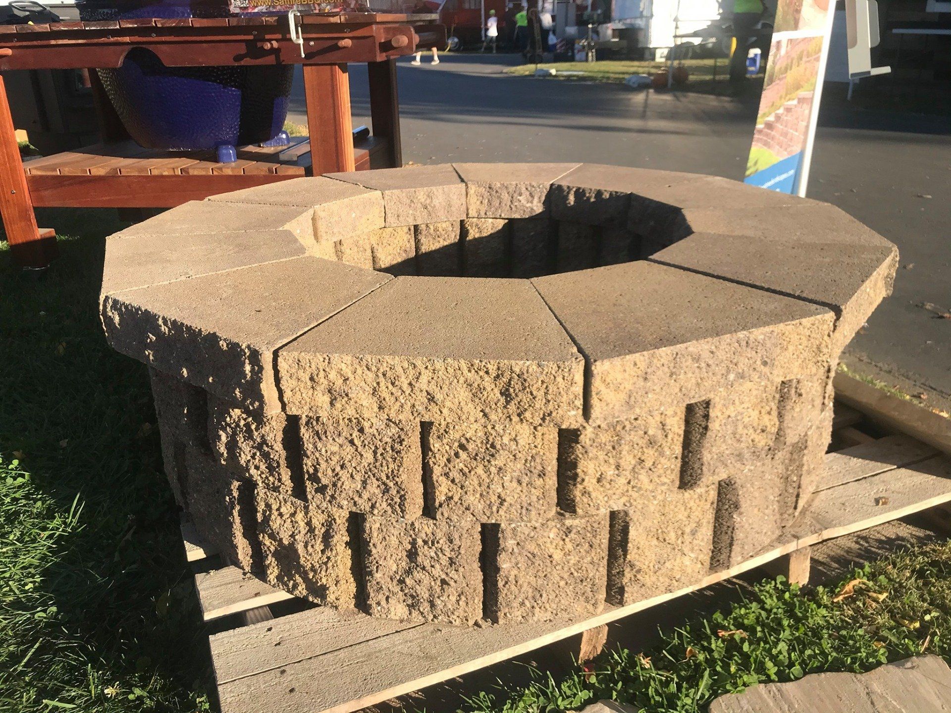 Octagonal concrete fire pit on a wooden pallet; brown blocks with textured sides.