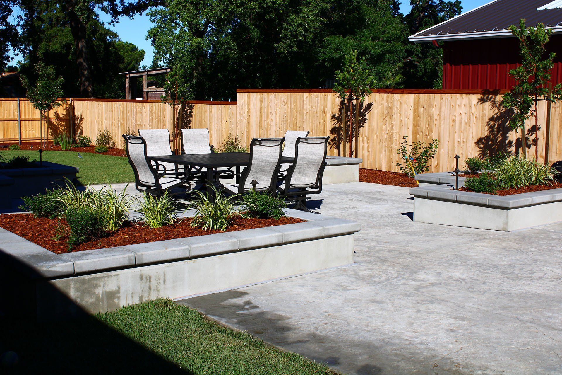 Patio with dining set, raised planters, wood fence, and lawn.