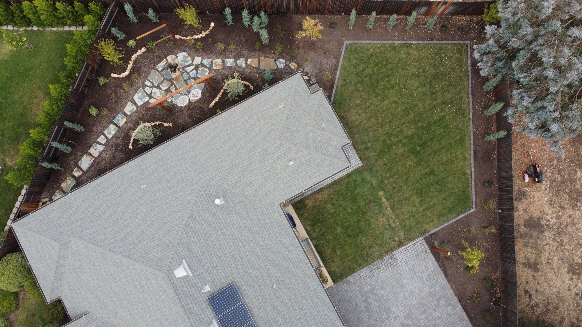 Overhead view of a house with a green lawn, rock garden, and driveway.