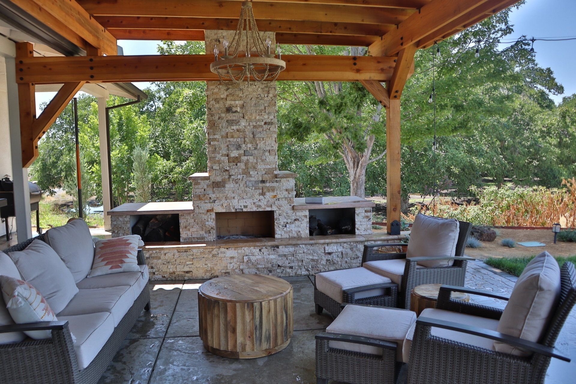 Patio with outdoor fireplace, seating, and wooden pergola.