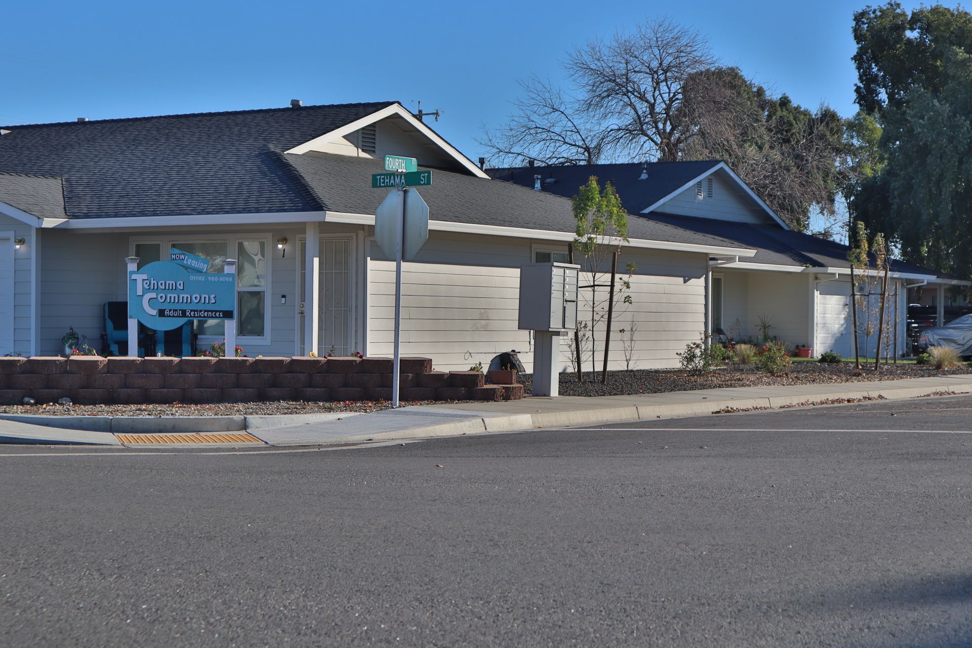 Corner of a commercial building with sign, beige siding, black roof, and street sign, on a sunny day.