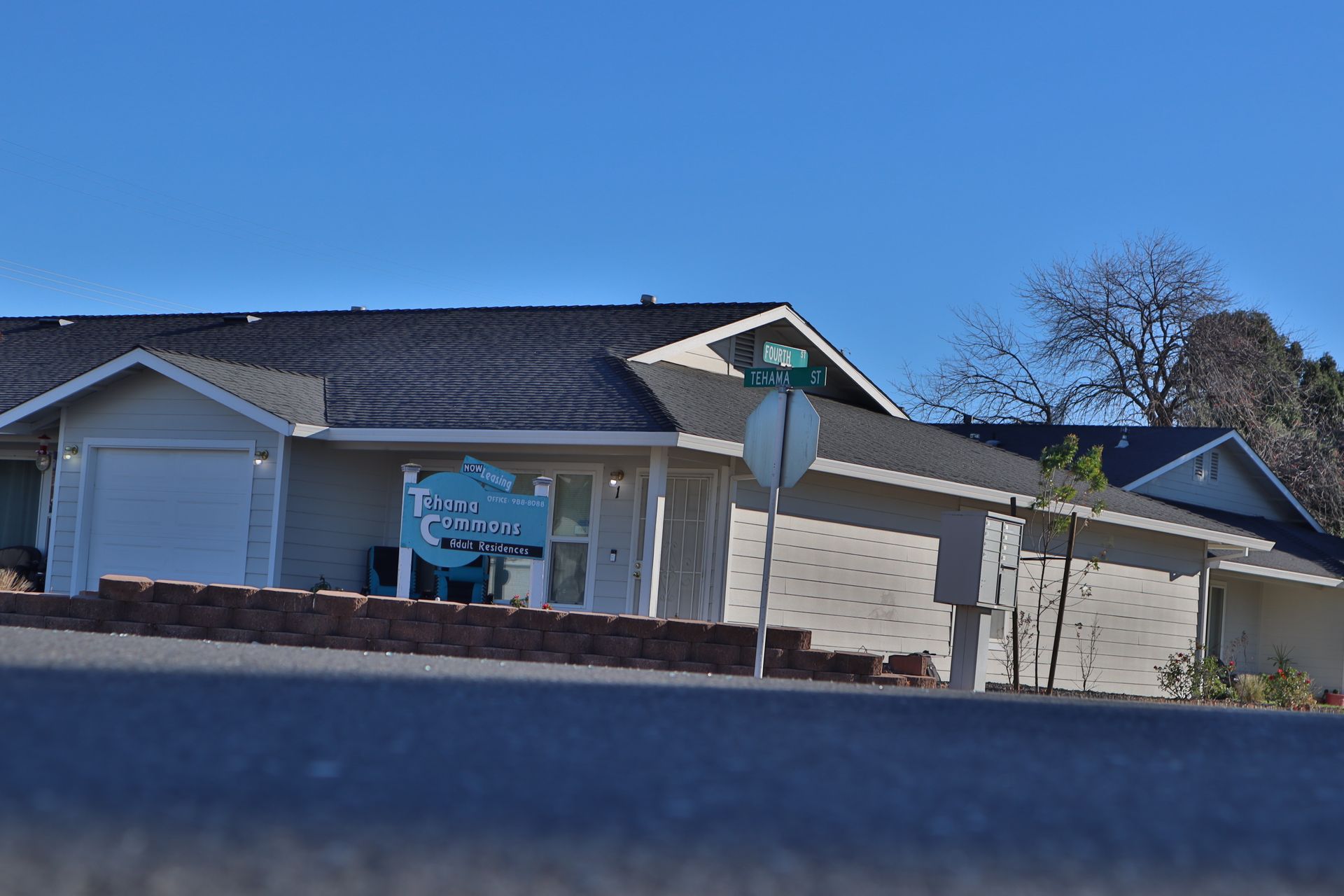 A light blue building with a dark roof and white garage doors, under a blue sky.