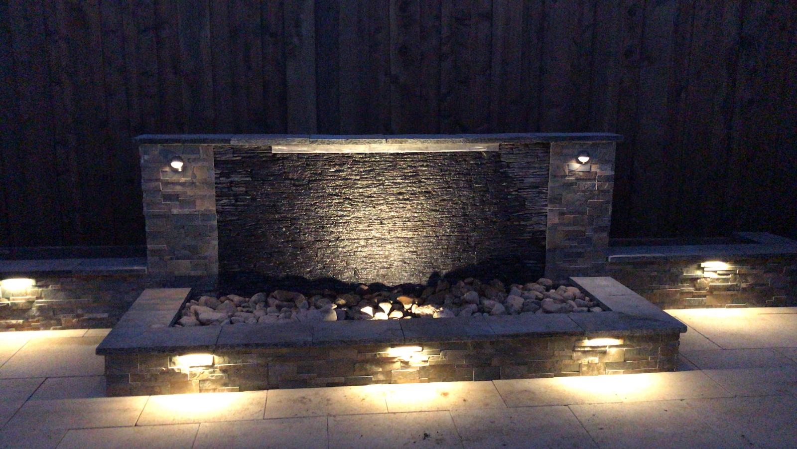Lit stone water feature at night with ambient lighting.