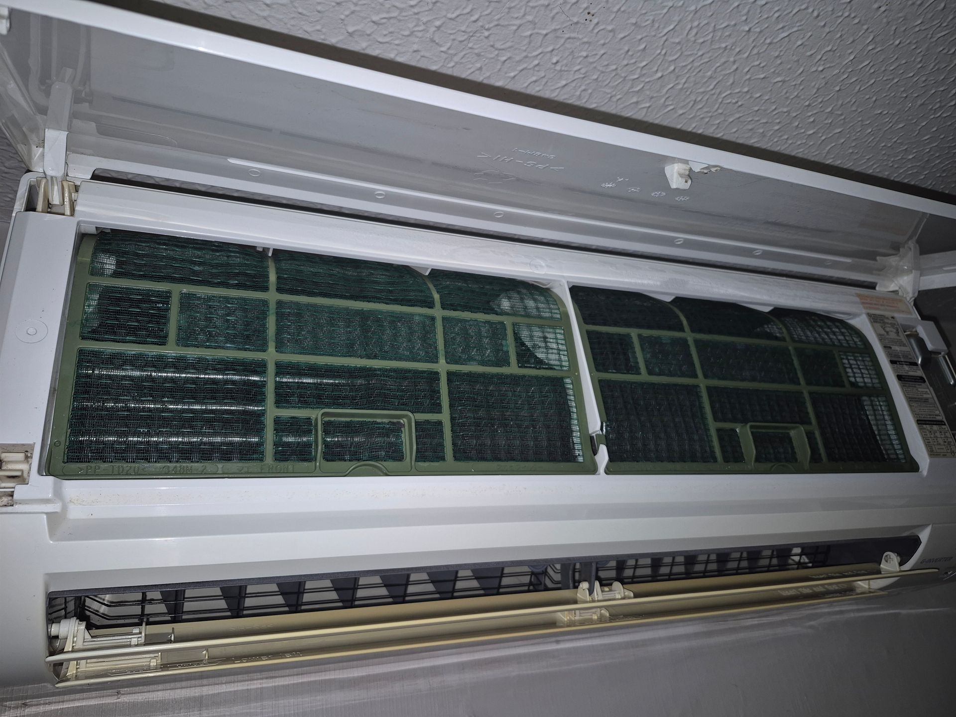 Air conditioner interior with two removable air filters, white frame, grimy.