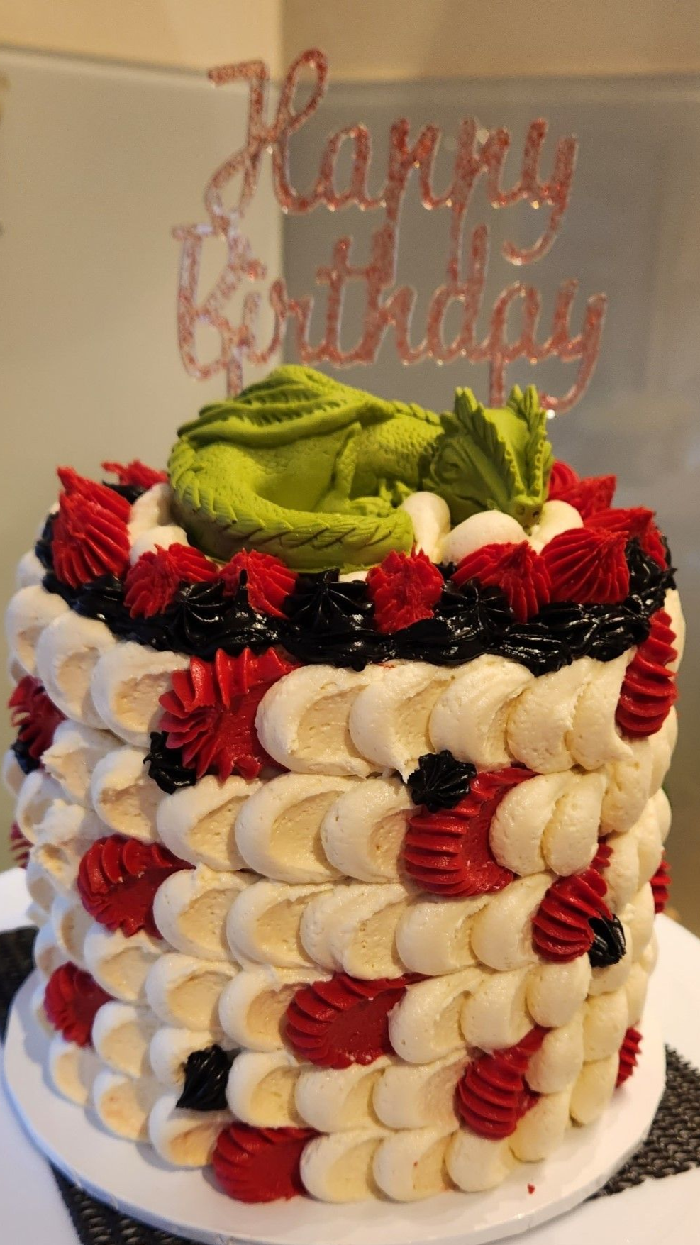 Birthday cake with green dragon topper and decorative icing.