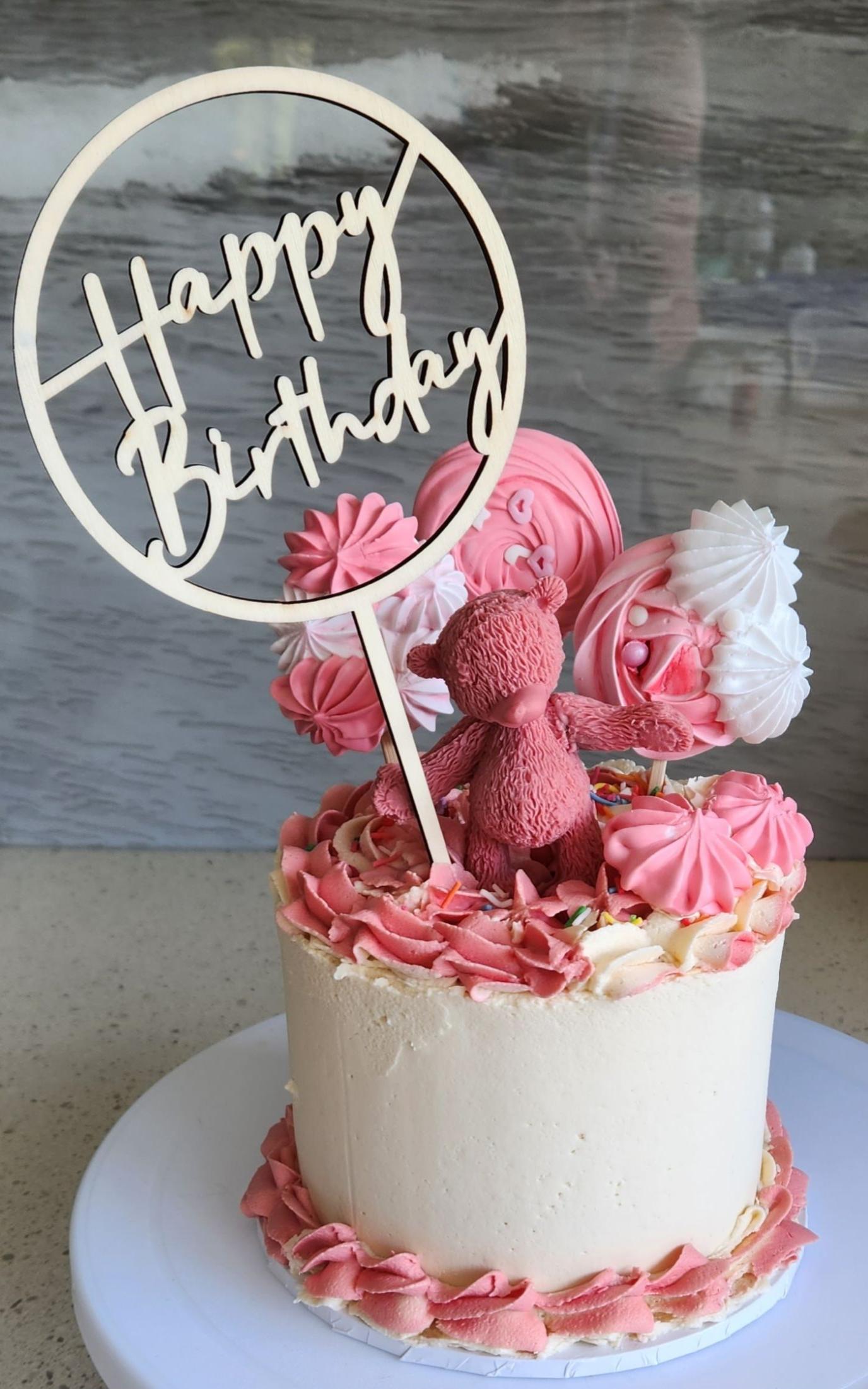 Birthday cake with pink frosting, decorations, and a 