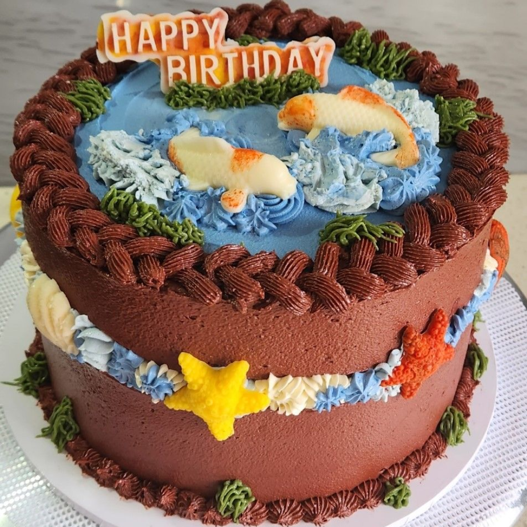 Birthday cake decorated with koi fish, blue water, and 