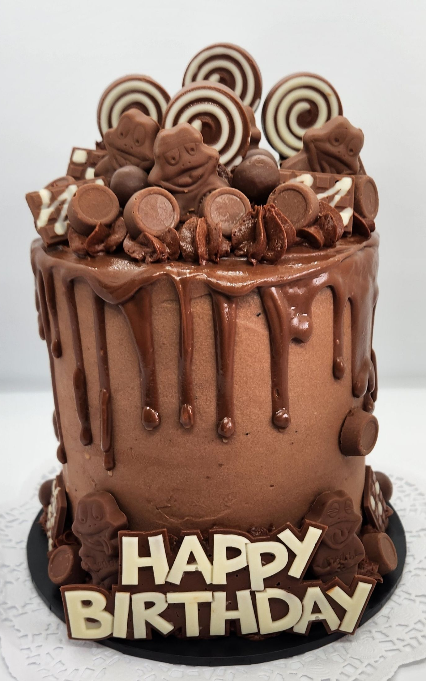 Chocolate birthday cake with chocolate drip, candies, and 