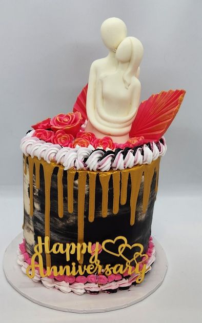 Anniversary cake with a white chocolate couple figurine, roses, gold drip, and 