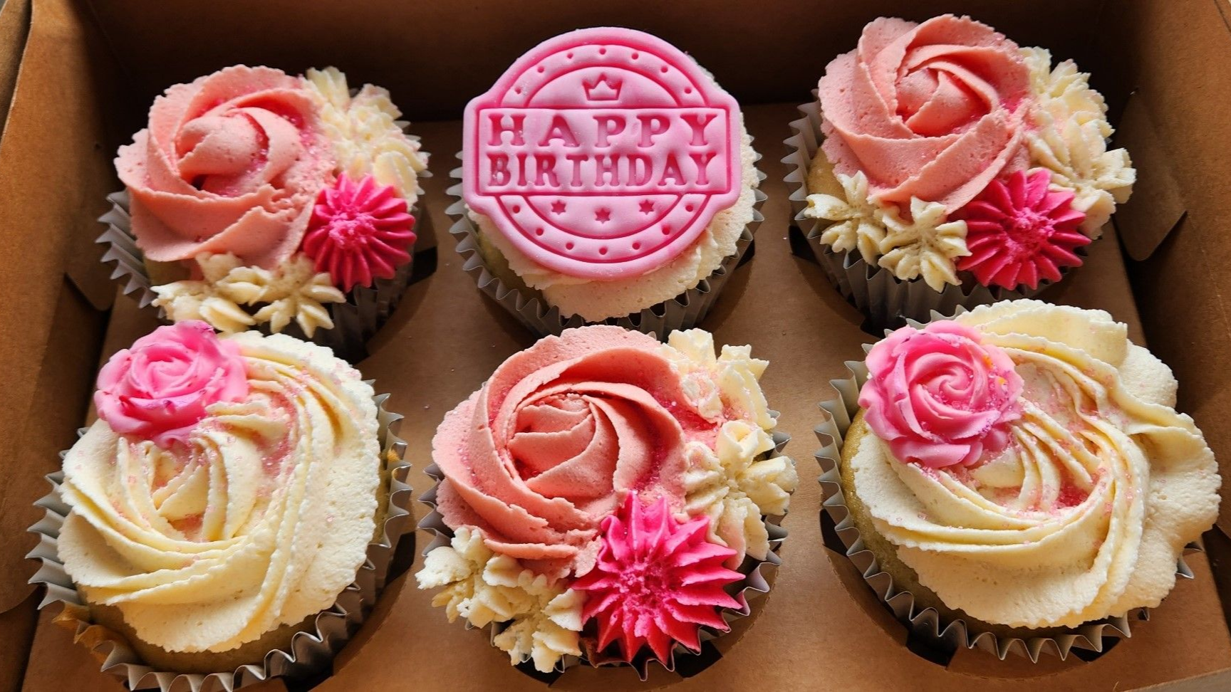 Six decorated cupcakes in a box: pink and white frosting roses, 