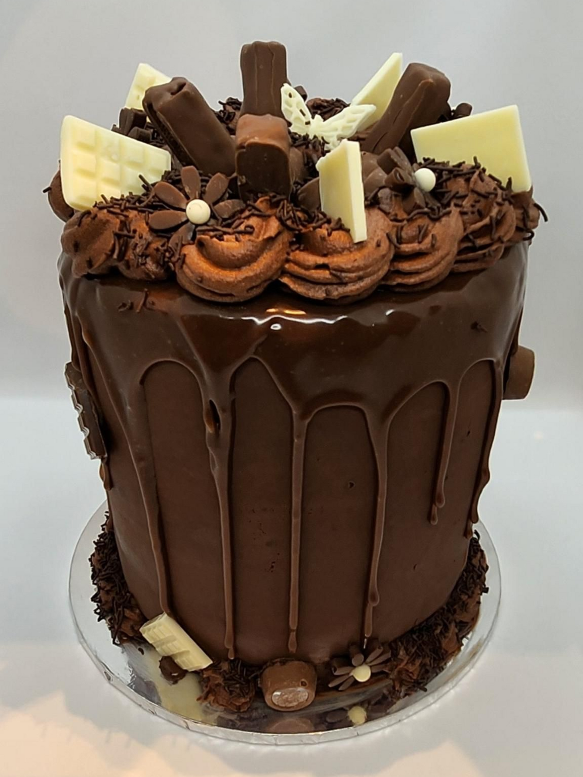 Chocolate cake with chocolate frosting, drip, and assorted chocolate and white chocolate decorations.