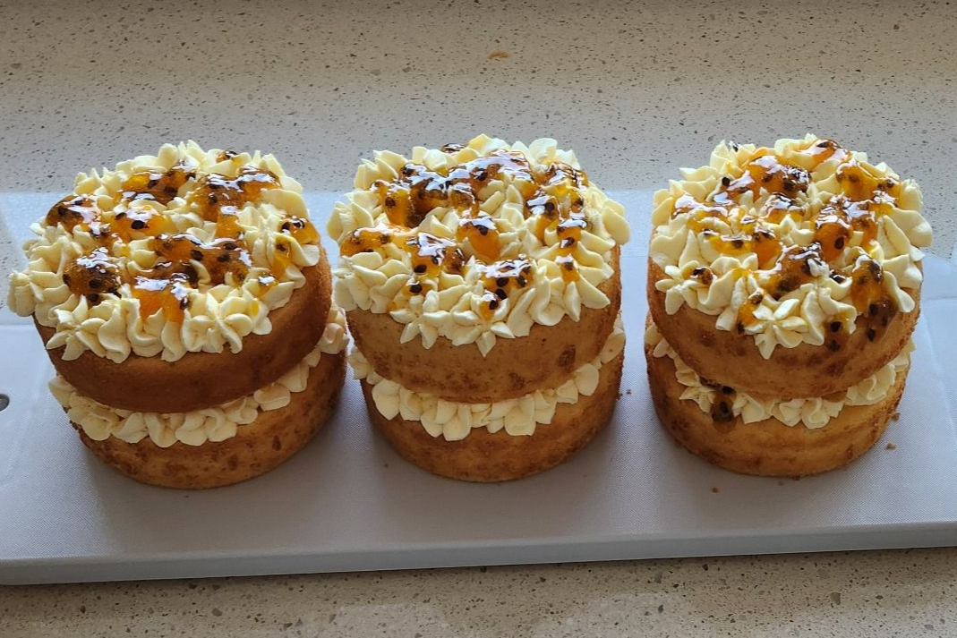 Three mini layered cakes with white frosting and passion fruit topping.