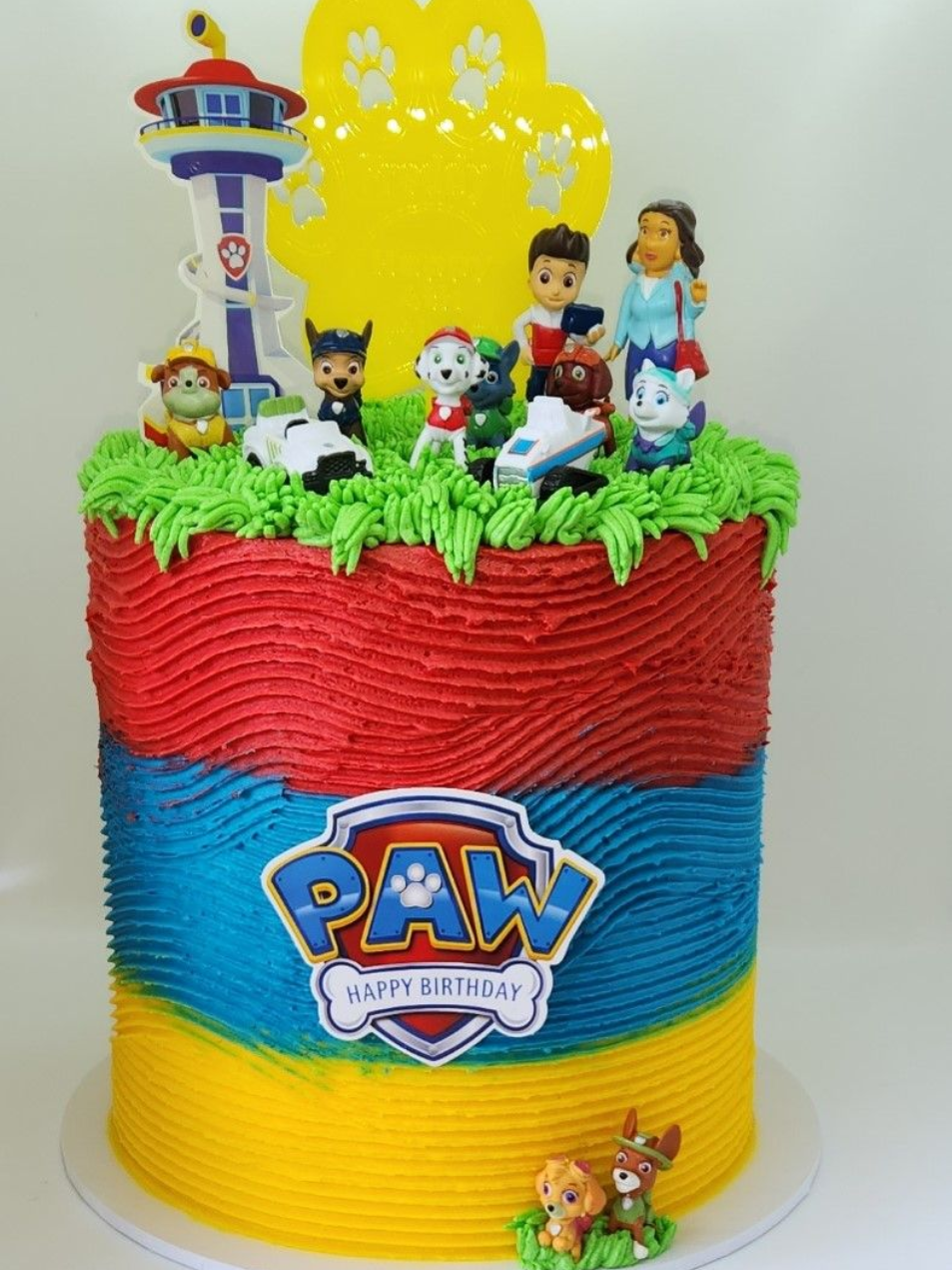 Paw Patrol birthday cake with figures, colorful frosting layers, and a tower.