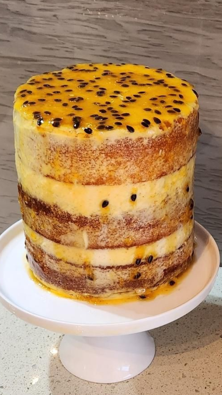 Layered cake with passion fruit topping, on a white cake stand.