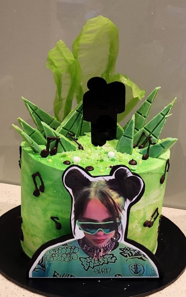 Billie Eilish-themed cake with green frosting, musical notes, and a photo cutout of the singer.