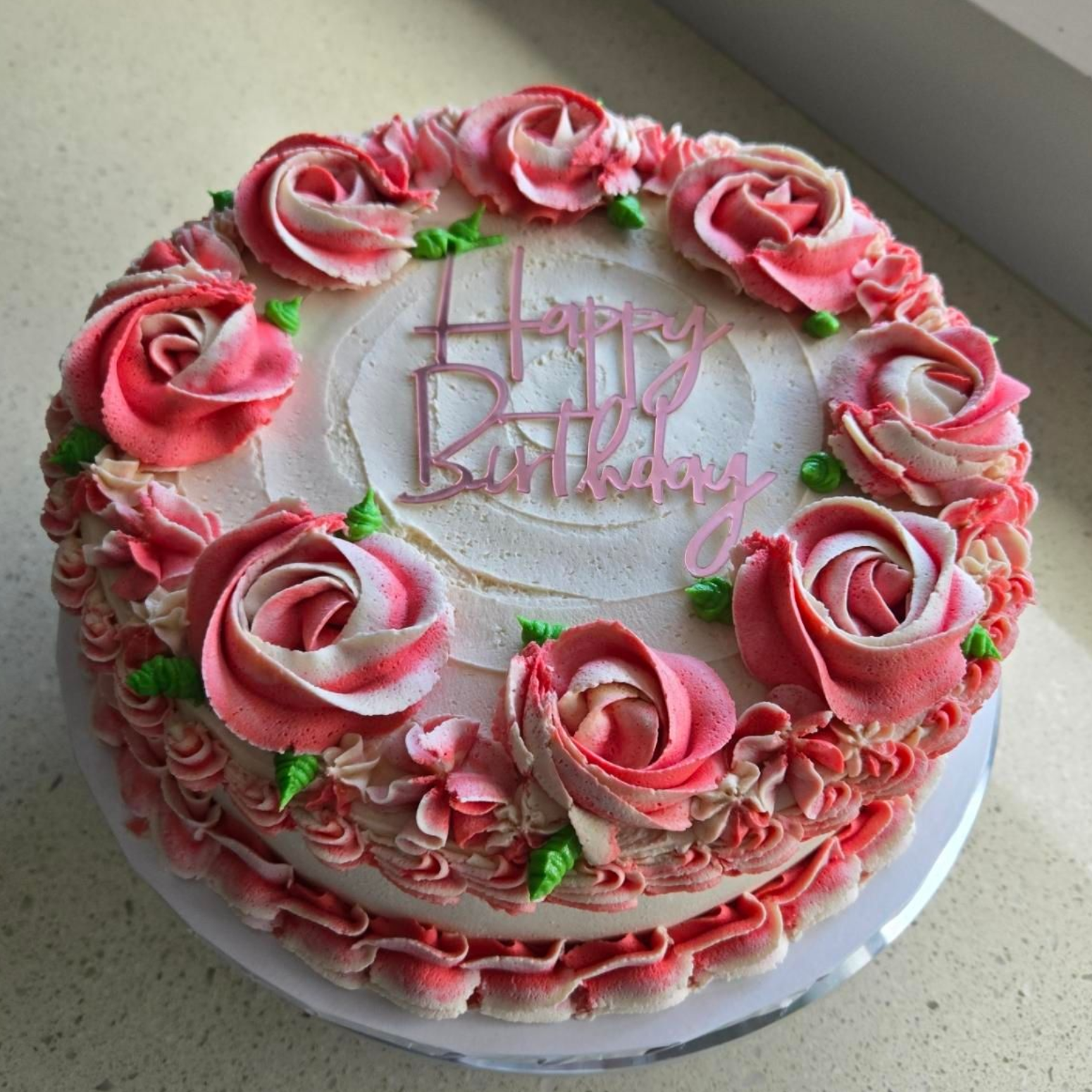 Pink rose-decorated birthday cake with 
