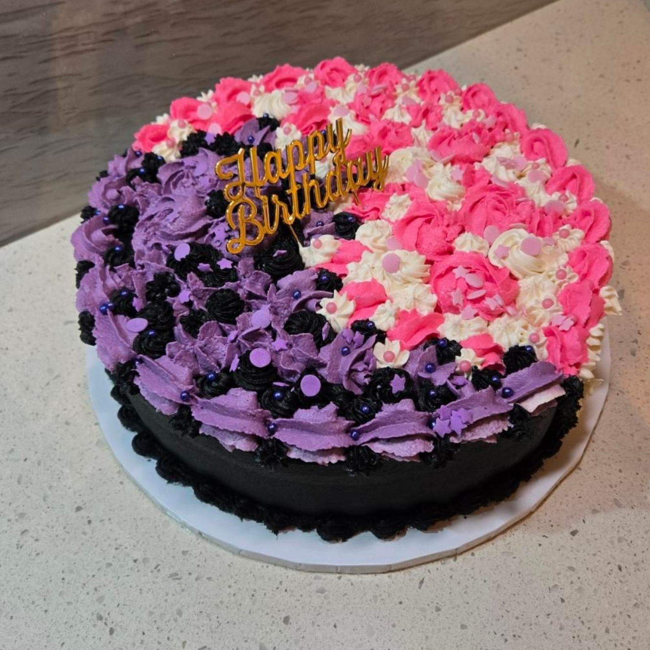 Birthday cake, half purple and pink frosting, black base, topped with 