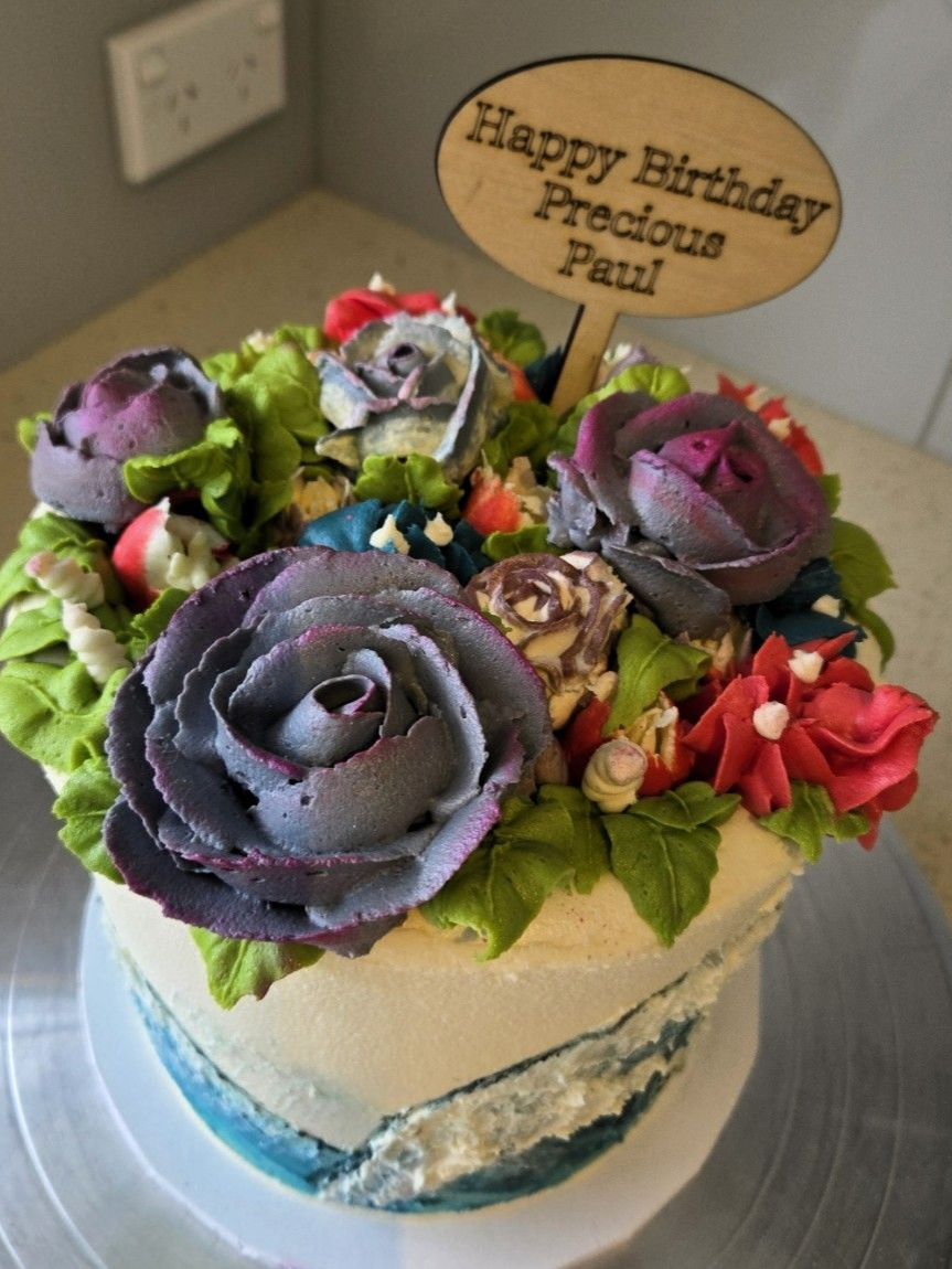 Cake decorated with buttercream flowers, a wooden 