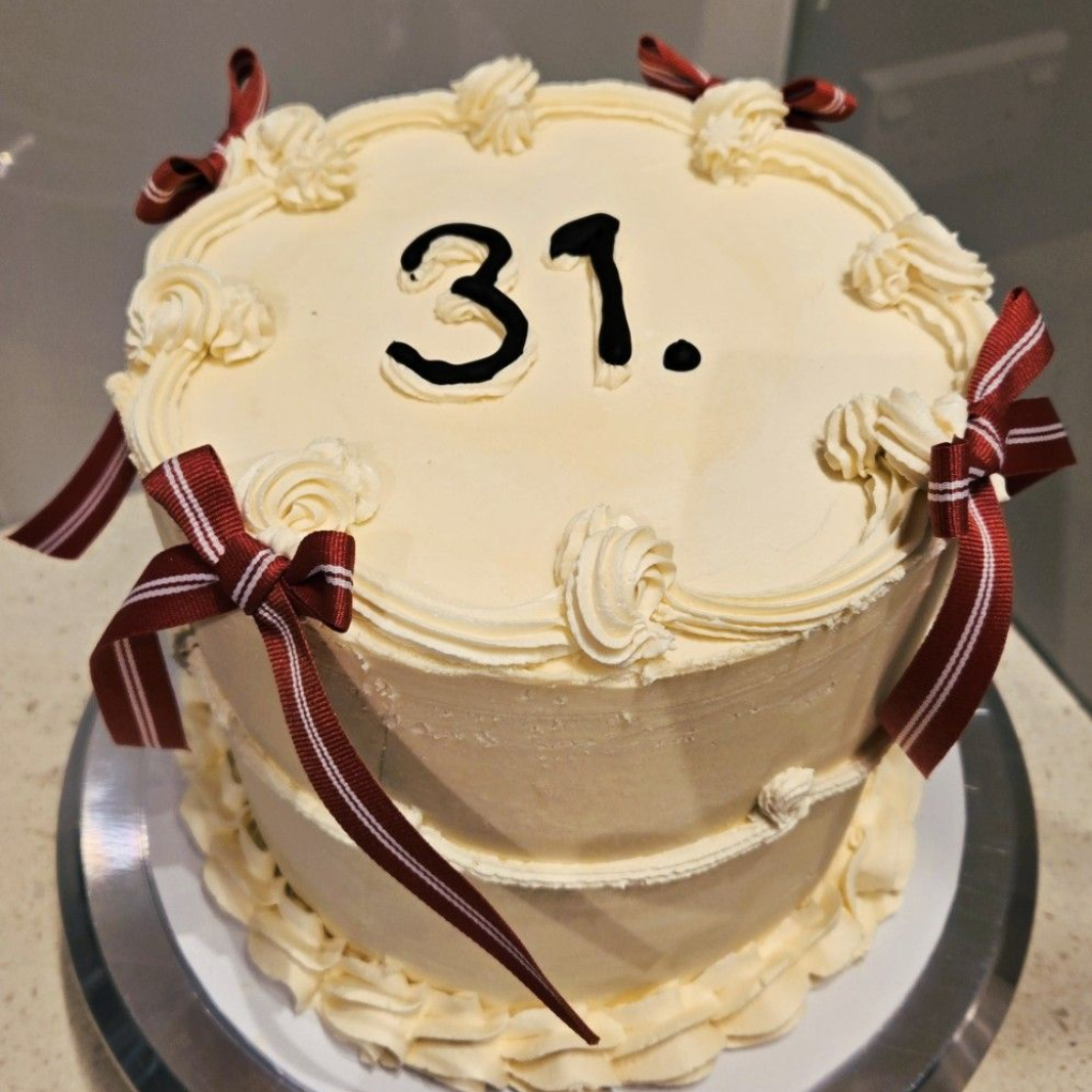 Cake decorated with white frosting and burgundy ribbon bows, 