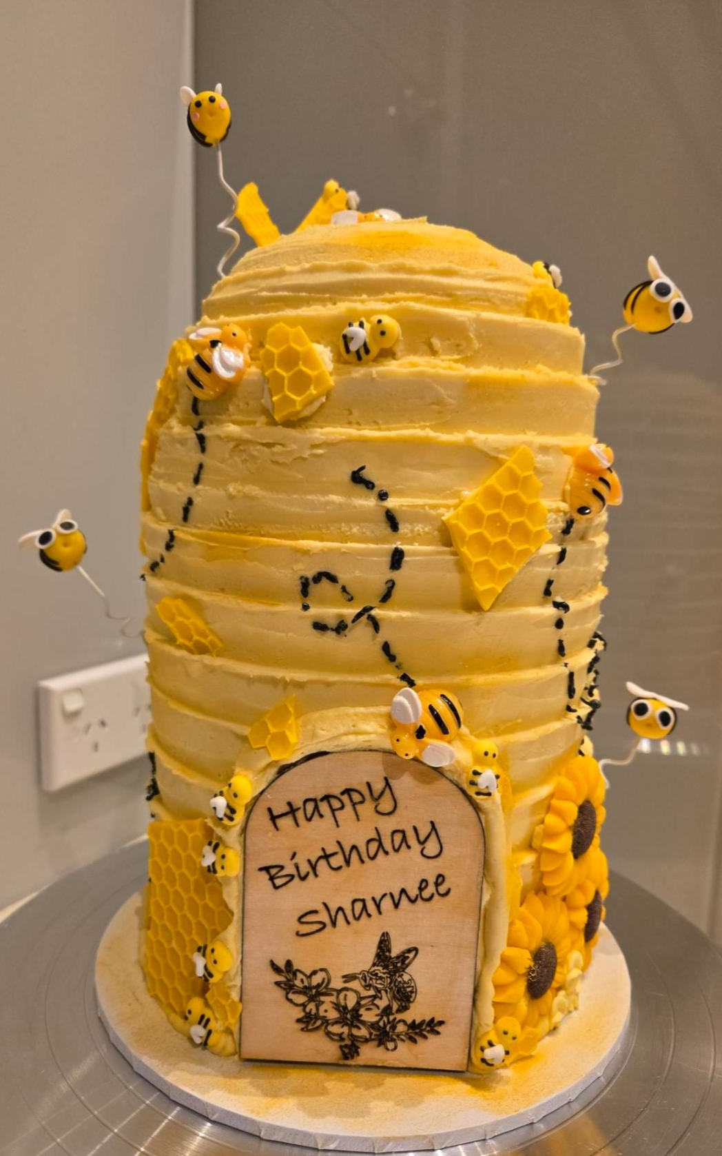 Beehive-shaped birthday cake with yellow frosting, bees, honeycomb, and a 