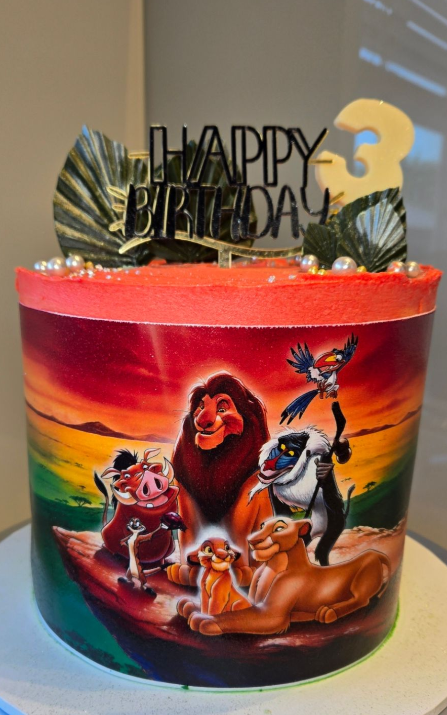 Lion King themed birthday cake with characters against sunset, topped with 
