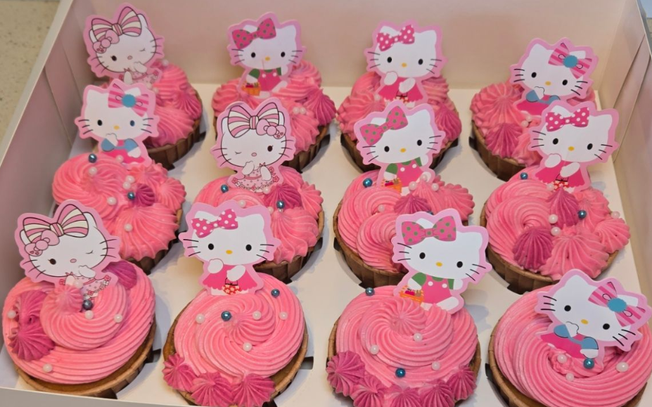 Box of pink frosted cupcakes with Hello Kitty toppers.