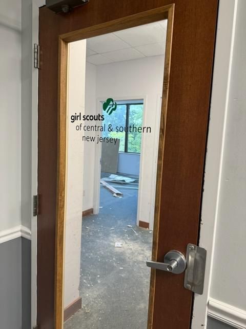 Open wooden door to an office with Girl Scouts of Central & Southern New Jersey logo on glass panel.