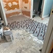 Bathroom under renovation with floor covered in tile spacers and construction debris