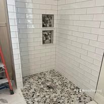 Custom walk-in shower with large-format tile, glass enclosure, and stone accents in a bright coastal bathroom.