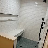 Small minimalist shower room with white tile, built-in bench, shelf, and handheld shower head.