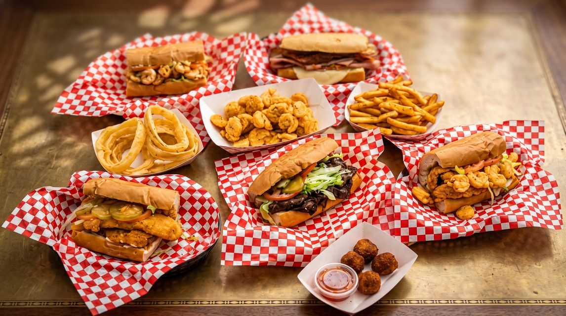 Basket of fried chicken and fries in a red tray lined with red-and-white checkered paper, with lemon wedges.