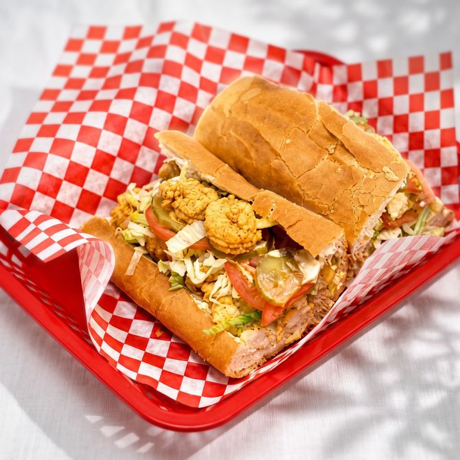 Sandwich in a red basket with red-and-white checkered paper on a white surface