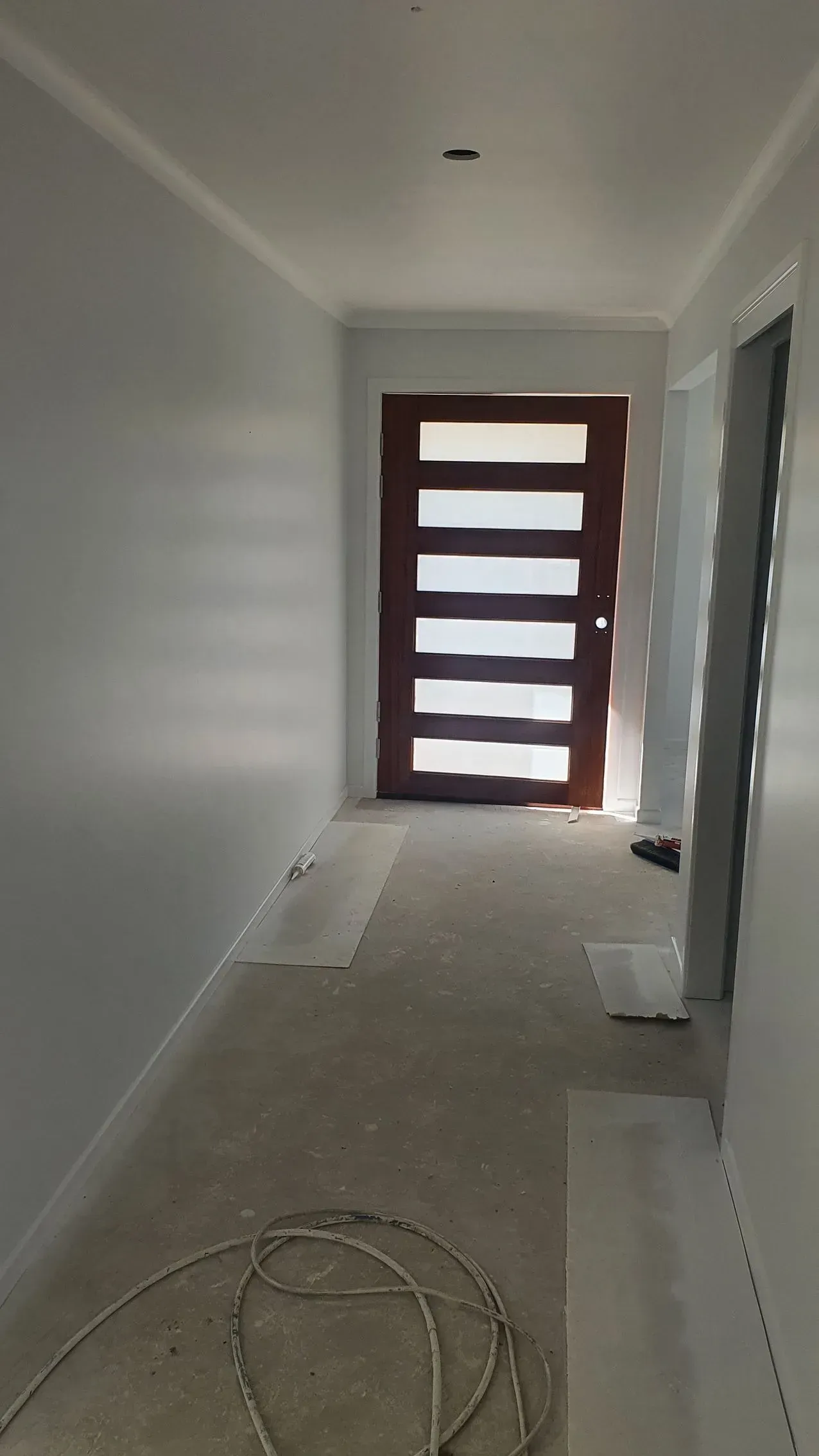 Hallway With Unfinished Concrete Floor, White Walls, Brown Door — Keppel Coatings in Pacific Heights, QLD